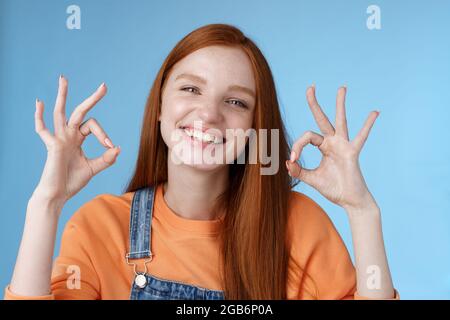 Wohlbefinden, Glück, Perfektion Konzept. Attraktive freundlich lächelnd fröhlich rothaarige weibliche Student zeigen ausgezeichnet okay ok Gesten grinsend Genehmigung Stockfoto