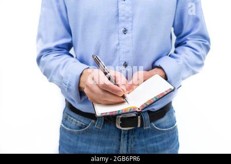 Mann in blauem Hemd und blauer Jeans, der mit einem Stift auf einem Papierkissen schrieb. Speicherplatz kopieren. Stockfoto