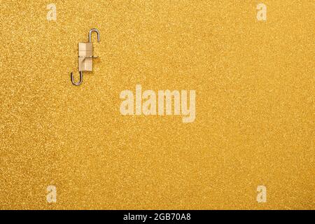 Kleine Vorhängeschlösser und Schlüssel auf goldfarbenem Hintergrund.das Foto hat einen Kopierraum und ist von oben aus gesehen.das Foto ist horizontal Stockfoto