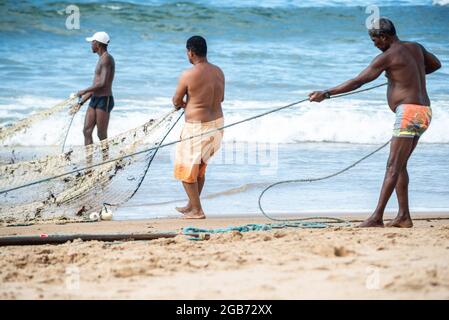 Salvador, Bahia, Brasilien - 23. Mai 2021: Fischer ziehen das Fischernetz aus dem Meer mit Fischen im Inneren. Strand von Boca do Rio in Salvador. Stockfoto