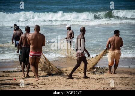 Salvador, Bahia, Brasilien - 23. Mai 2021: Fischer ziehen das Fischernetz aus dem Meer mit Fischen im Inneren. Strand von Boca do Rio in Salvador. Stockfoto