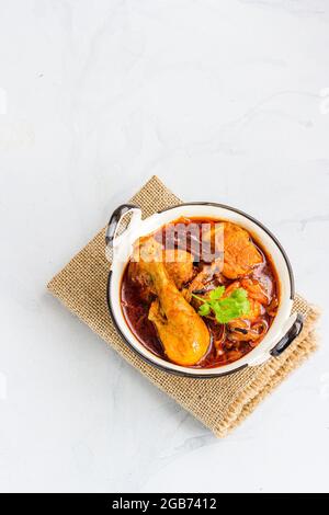 Indian Spiced Chicken Curry in einem Kadai auf weißem Hintergrund direkt über Indian Food Foto Stockfoto