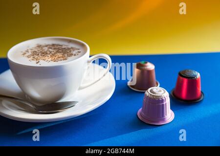 Tasse Espresso mit Pads und Kapseln auf braunen Holztisch serviert. Ansicht von oben Stockfoto