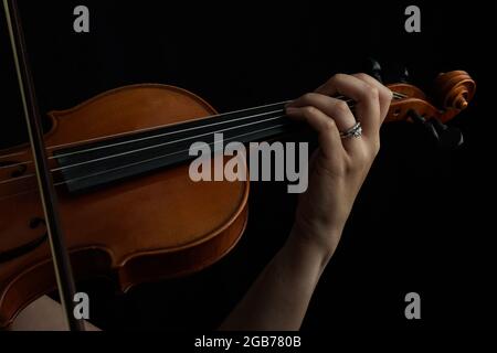 Nahaufnahme einer Frau, die im Dunkeln Violine spielt Stockfoto