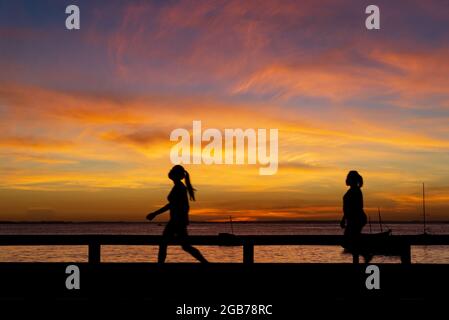 Salvador, Bahia, Brasilien - 27. Mai 2021: Silhouette von Menschen, die am Strand von Ribeira spazieren, laufen, reden und den Sonnenuntergang genießen. Stockfoto