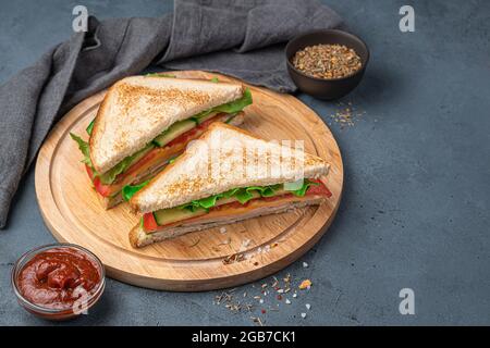 Zwei Sandwiches mit gebratenem Brot, Schinken, Käse und Gemüse auf dunkelblauem Hintergrund. Seitenansicht, Kopierbereich Stockfoto