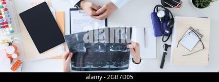 Arzt und Patient besprechen die Röntgenaufnahme am Arbeitstisch Stockfoto