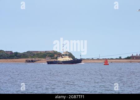 Schleppboot Svitzer Shotley unterstützt ein Containerschiff, das den Hafen von Felixstowe, Suffolk, Großbritannien verlässt. Stockfoto