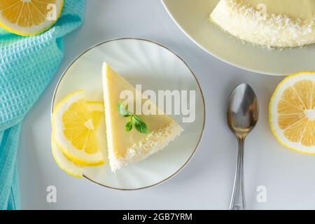 Ein Stück Biskuit-Dessert mit Zitronen- und Kokosflocken. Geschichteter Vanillekuchen auf einem weißen Teller. Stockfoto