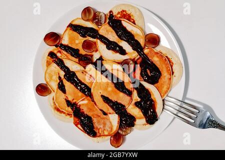 Hausgemachte glutenfreie Pfannkuchen mit Schokoladensauce auf einem weißen Teller. Stockfoto