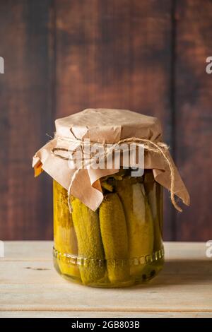 Eingelegte Gurken in einem Glas auf Holzgrund. Fermentierte Trendfutter. Haus rustikalen Stil. Stockfoto