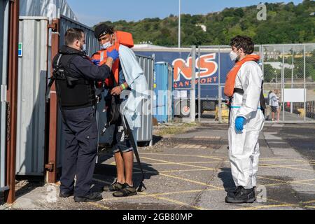 Dover, Großbritannien. August 2021. Eine Grenztruppe hilft einem Migranten, die Rettungsweste auszuziehen, nachdem er in Dover an Land gebracht wurde.Trotz der größten Anstrengungen der britischen Regierung, die illegalen Übergänge zu stoppen, überqueren täglich immer noch viele Menschen den Ärmelkanal. Kredit: SOPA Images Limited/Alamy Live Nachrichten Stockfoto