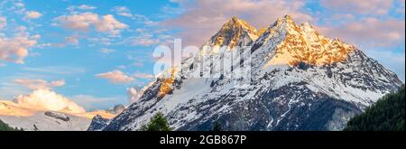 Alpine Berglandschaft oberhalb des Val Herens in der Schweiz bei Sonnenuntergang mit schneebedeckten Gipfeln und einer sehr großen Wolke Stockfoto