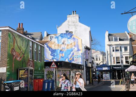 Modische junge Mädchen kommen an dem Wandgemälde „Angels“ von REQ vorbei, einem Auftragswerk, das dem NHS und seinen Arbeitern in Brighton, England, Großbritannien, Tribut zollt Stockfoto