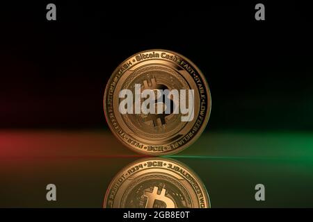 Bitcoin Cash BCH Kryptowährung physische Münze auf reflektierender Oberfläche platziert und mit grünen und roten Lichtern beleuchtet Stockfoto