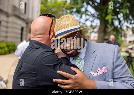 2. August 2021; Bloomington, Indiana: Vauhxx Booker, rechts, Wird nach einem Gespräch während einer Pressekonferenz umarmt, nachdem ihm ein Spezialanwalt über ein Jahr nach einem Angriff am 4. Juli 2020 am Monroe-See am Montag, den 2. August 2021 im Monroe County Courthouse in Bloomington, Indiana, eine Straftat und Übertretung vorgeworfen hatte. Booker sagte, dass er von hinten von einer Gruppe angegriffen wurde, darunter zwei weiße Männer, die auf einem Video aufgezeichnet wurden, das ihn Angriff. Das Video wurde auf der ganzen Welt gesehen, und die Männer wurden wegen Verbrechen einschließlich Angriff angeklagt, aber jetzt hat ein Staatsanwalt auch Vauhxx kartiert, der sagte Stockfoto