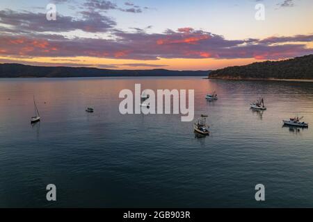 Fischerboote und Sonnenaufgang in Brisk Bay vom Patonga Beach an der Central Coast von NSW, Australien. Stockfoto