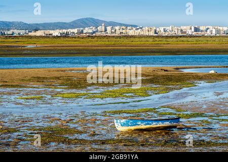 Boot durch die Feuchtgebiete der Ria Formosa bei Ebbe, Stadt Faro im Hintergrund, Algarve, Portugal Stockfoto