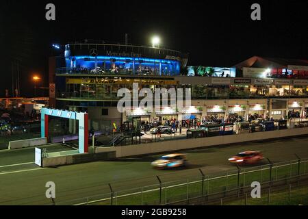 Beleuchtete Boxengasse, davor der Start und das Ziel direkt in der Nacht während des 24-Stunden-Rennens am Nürburgring, Nürnberg Stockfoto