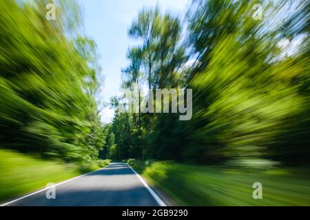 Blick durch die Windschutzscheibe eines fahrenden Autos auf kurvenreicher Landstraße, Weserbergland, Niedersachsen, Deutschland Stockfoto