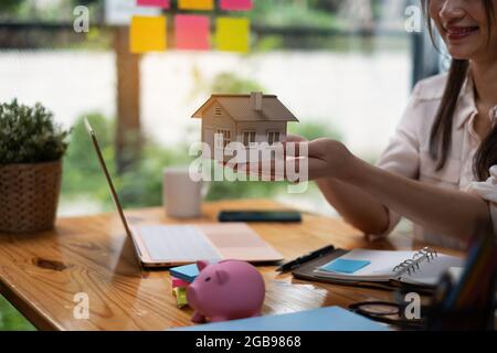 Ein Immobilienmakler demonstriert das Haus-Modell für Kunden, die sich für den Kauf einer Hausversicherung interessieren. Das Konzept der Hausversicherung und Immobilien Stockfoto