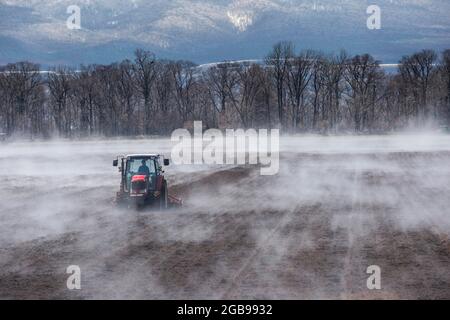 Traktor sät ein Feld, während es vom warmen Boden verdampft, UNESCO-Weltkulturerbe Shiretoko National Park, Hokkaido, Japan Stockfoto