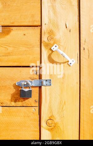 An der Holztür des Hauses hängt ein Metallvorhängeschloss Stockfoto