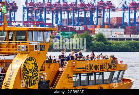 Hamburg, 22. Juli 2021: Touristen auf einem gelben Ausflugsboot im Hafenbecken fotografieren die Kraniche des Containerhafens Stockfoto