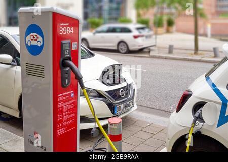 Hamburg, 22. Juli 2021: Autos mit elektrischem Antrieb werden über Kabel von einer Ladestation mit elektrischer Energie versorgt Stockfoto