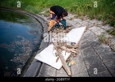 Emden, Deutschland. Juni 2021. Björn Fuhlendorf, Mitarbeiter von NPorts, sammelt Müll, der im Hafen aufgespült wurde. Mehrere niedersächsische Städte planen, ihre Häfen in naher Zukunft mit den sogenannten Marine-Abfallbehältern auszustatten. Eine Tauchpumpe unter einem Korb saugt permanent Wasser an. Treibgut, das auf der Wasseroberfläche in der Nähe schwimmt, wird angesaugt und fällt in das Auffangnetz. Das Wasser fließt zurück in das Hafenbecken. Quelle: Sina Schuldt/dpa/Alamy Live News Stockfoto