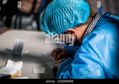 Bogota, Kolumbien. August 2021. Ein Mitarbeiter des Gesundheitspersonals füllt das „Mi Vacuna“-Zertifikat aus, nachdem Patienten den Impfstoff Moderna COVID-19 erhalten haben, da Fahrer des öffentlichen Verkehrs und Menschen im Alter von 25 bis 30 Jahren am 2. August 2021 in Bogota, Kolumbien, ihre Impfphase mit dem neuartigen Impfstoff Moderna COVID-19 gegen die Coronavirus-Krankheit beginnen. Kredit: Long Visual Press/Alamy Live Nachrichten Stockfoto