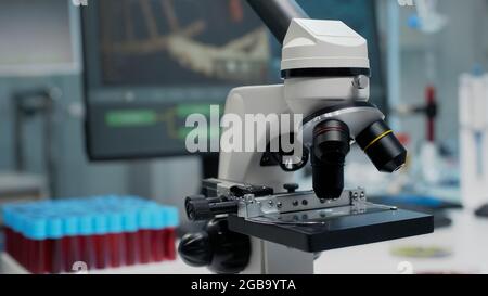 Nahaufnahme der mikroskopischen Glaslinse im Labor der chemischen Klinik. Von Wissenschaftlern für die Blut- oder Substanzuntersuchung verwendetes Gerät für die Mikrobiologie. Staubsauger und Computer auf dem Schreibtisch Stockfoto