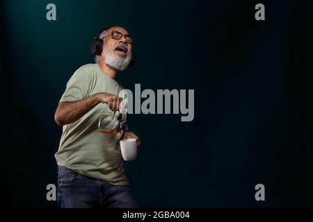 EIN GLÜCKLICHER ALTER MANN VERSCHÜTTETE KAFFEE, WÄHREND ER ZUR MUSIK TANZTE Stockfoto