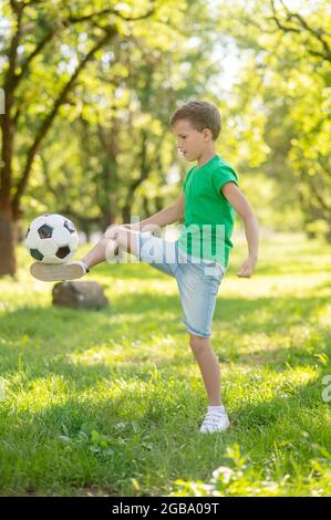 Junge trifft Fußball auf dem Rasen Stockfoto
