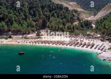 Ansicht von oben, aus der Vogelperspektive ein Smaragd und transparente Mittelmeer mit einem weißen Strand mit Sonnenschirmen und Touristen, die Entspannen und swi Stockfoto