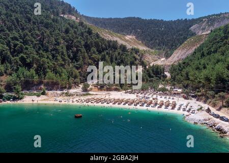 Ansicht von oben, aus der Vogelperspektive ein Smaragd und transparente Mittelmeer mit einem weißen Strand mit Sonnenschirmen und Touristen, die Entspannen und swi Stockfoto