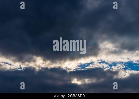 Lichtstrahlen, die durch dunkle Wolken leuchten.schöner dramatischer Himmel mit Sonnenstrahlen.dramatischer Himmel mit Sonnenstrahlen. Stockfoto