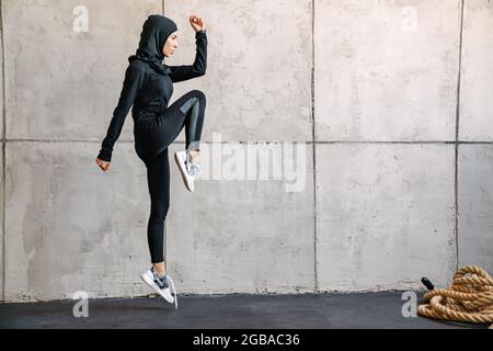 Junge muslimische Frau im Hijab, die beim Training in Innenräumen springt Stockfoto