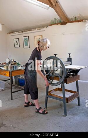 Die britische Künstlerin Vivian Kersey arbeitet an einem Linolschnitt auf einer Littljohn-Radierpresse in ihrer Druckwerkstatt Carmarthenshire Wales UK KATHY DEWITT Stockfoto