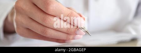 Der Arzt schreibt die Krankengeschichte des Patienten mit einem Stift auf die Karte Stockfoto