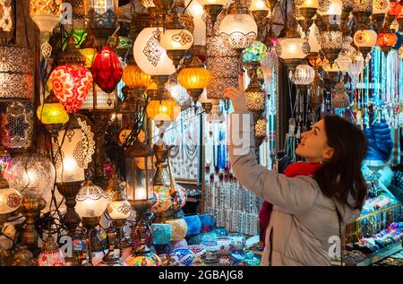 Junge Frau berührt türkische Lampen zum Verkauf im Großen Basar, Istanbul, Türkei Stockfoto