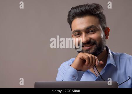 EIN BÄRTIGER JUNGER MANN POSIERT FRÖHLICH VOR DER KAMERA Stockfoto