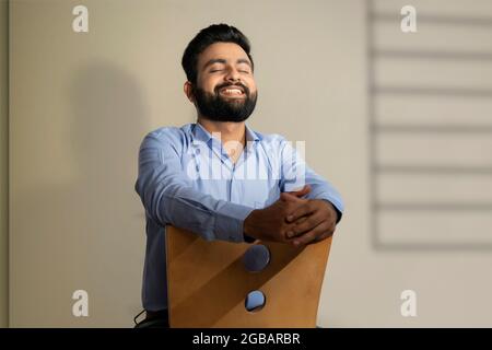 EIN GLÜCKLICHER BÄRTIGER MANN, DER SITZT UND SICH GLÜCKLICH FÜHLT Stockfoto