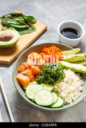 Lachs mit Avocado, Algen, eingelegten Karotten und Gurken auf Betontisch. Stockfoto
