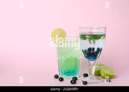 Gläser mit frischen Sommercocktails und Zutaten auf rosafarbenem Hintergrund Stockfoto