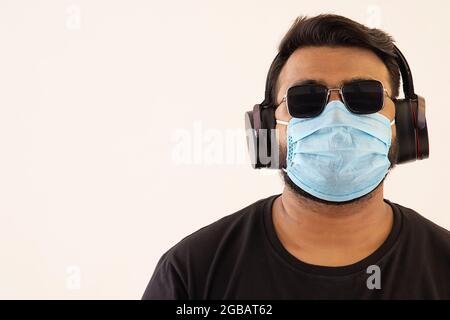 Porträt eines jungen Mannes mit Kopfhörern und Maske im Gesicht. Stockfoto