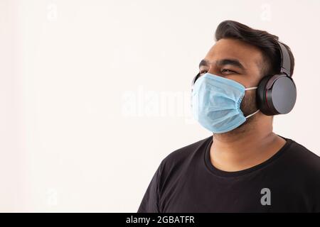 Porträt eines jungen Mannes mit Kopfhörern und Maske im Gesicht. Stockfoto