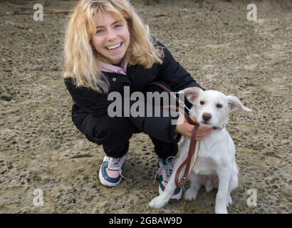 Porträt eines glücklichen Teenager-Mädchens 16-17 Jahre alt spielt mit ihrem weißen Hund im Freien, geliebtes Haustier Training. Die Freude, mit einem Welpen zu kommunizieren. Walki Stockfoto