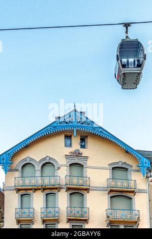 Eine Gondelbahn, die vor einem Haus in der Bergstadt Cauterets im Nationalpark der Pyrenäen in Frankreich vorbeifährt Stockfoto