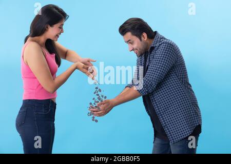 Ein junger Mann fängt Münzen, die von den Händen einer Frau fallen. Stockfoto